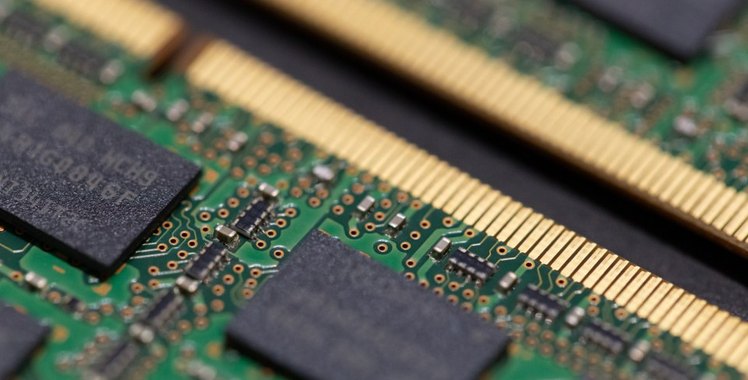 Close-up of a memory module — black chips on a green board above a row of gold contacts