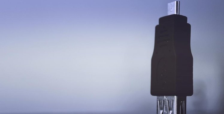 A black USB security key standing upright against a pale blue background